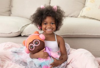 Young girl wearing headphones holding doll wearing headphones