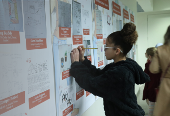 Girl standing at a board covered in papers