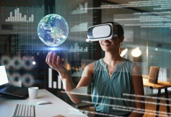 Woman in an office wearing VR goggles looking at an image of the world