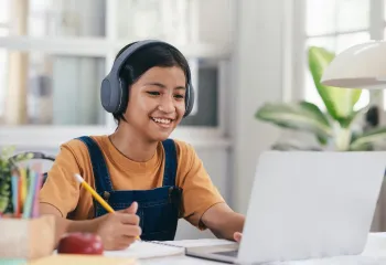 Photo of girl wearing headphones looking at a laptop