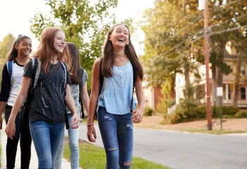 Group of teen girls wearing backpacks walking on a street