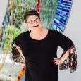 Woman with short, dark hair wearing glasses and black shirt