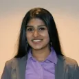 Varshini Odayar - woman with dark hair wearing gray blazer and purple shirt