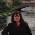 Celia Dominguez - Woman with dark hair standing in front of a river and bridge