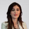 Gulan Gawdan headshot - woman with long dark hair wearing tan blazer