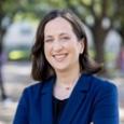 Allison Master Headshot - woman with dark hair, wearing blue blazer, with trees in the background