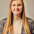 Emma Stockwell - woman with long blond hair wearing tan shirt with a plaid blazer