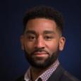 Darryl Williams - headshot of man with short, curly, dark hair and beard in front of blue background