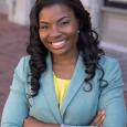 Nikole Collin Puri - woman with long black hair wearing blue blazer and yellow shirt