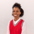 Ora Tanner - woman with curl dark hair wearing red sweater vest over a white shirt