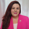 Annie Stikeleather, woman with long red-brown hair and wearing a pink blazer