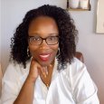 April Caldwell - Woman with curly black hair and glasses wearing white shirt