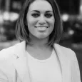 Janna Mino - black and white photo of a woman with dark hair wearing a white shirt and blazer