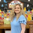 Anna Bottoms - Woman with curly blond hair standing in front of a library display