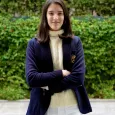 Teen girl with brown hair wearing navy blazer and cream sweater