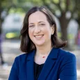 Photo of Allison Master - woman with shoulder length brown hair wearing navy blazer and black shirt. 